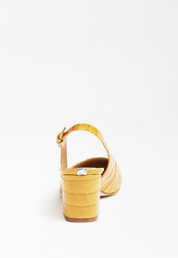 Sandales à talons jaunes gaufrées crocodile avec une bride de cheville et un talon carré. Le talon a une finition brillante et une semelle contrastante.