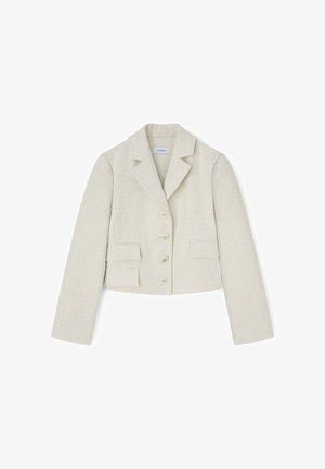 Blazer court texturé de couleur crème avec revers à encoche, quatre boutons et deux poches à rabat, posé à plat sur un fond blanc.