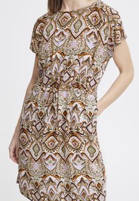 Vestido de manga corta en tejido estampado con diseños intrincados en tonos tierra, con cintura ajustada y bolsillos.
