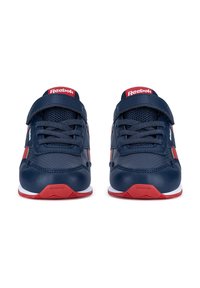 Un par de zapatillas Reebok en azul marino y rojo con cordones y una correa de Velcro, vistas desde el frente sobre un fondo blanco.