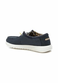 Zapato deslizante de malla azul marino con suela de goma blanca, acentos amarillos y azules, forro interior a cuadros y parte superior de textil azul marino.