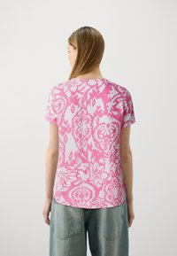 T-shirt rosa a maniche corte con un motivo floreale e paisley bianco, realizzato in un tessuto morbido con una vestibilità comoda.
