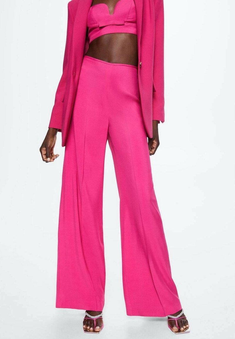 Ensemble blazer fuchsia et pantalon à larges jambes, mettant en avant un tissu lisse et des accents minimalistes. La tenue a un design structuré, avec un haut ajusté.