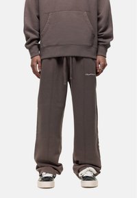 Oversized gray hoodie with a front pocket, paired with loose gray sweatpants featuring drawstring waist and embroidered logo.