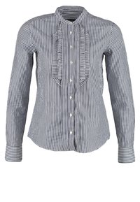Chemise à manches longues boutonnée avec rayures verticales noires et blanches et détails froncés le long de la ligne de boutons à l'avant.