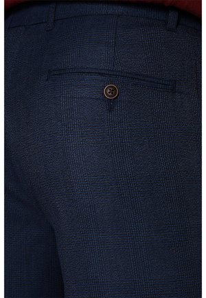 Granatowe spodni w kratę z tylną kieszenią zapinaną na brązowy guzik, wykonane z teksturowanego materiału dla dodatkowego efektu.