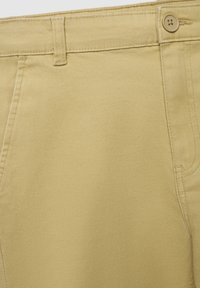 Beżowe bawełniane spodnie o gładkiej teksturze, z zapięciem na guzik i szlufkami na pasek. Projekt zawiera boczne kieszenie i prosty krój.