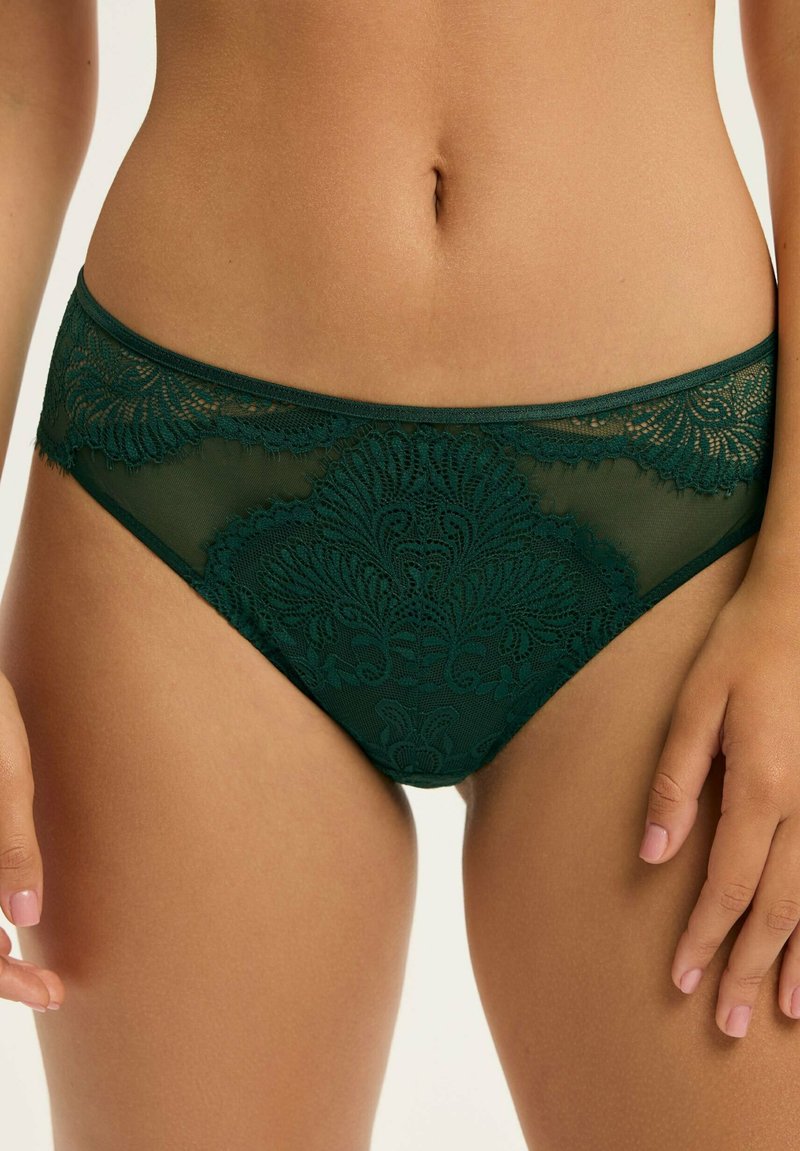 Grüne Spitzenunterwäsche mit floralem Muster, ausgestattet mit einem durchsichtigen Mesh-Design, elastischem Taillenbund und filigranen Details entlang der Ränder.