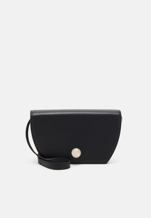 Schwarze Leder-Clutch mit geschwungener Form, ausgestattet mit einem Knopfverschluss im Perlenstil und einem abnehmbaren Tragegurt. Glatte Textur, minimales Design.