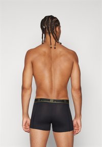 Boxers pretos com uma cintura larga em verde-oliva, apresentando "PUMA" em preto. Tecido suave e ajuste justo, vistos de costas.