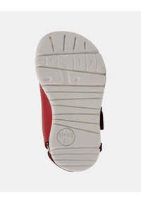 Sandal in pelle rossa con un design curvo, dotata di una suola in gomma bianca. I contorni del battistrada testurizzato e un logo "Camper 21" sono visibili.