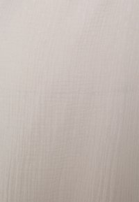 Light beige fabric with a textured, slightly crinkled surface, featuring subtle lines and a soft, airy appearance.