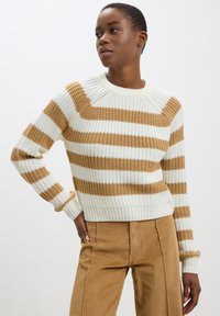 Maglione lavorato a maglia con righe verticali bianche e beige, polsini e orlo a coste, girocollo e finitura texturizzata. Abbinato a pantaloni in corduroy beige.
