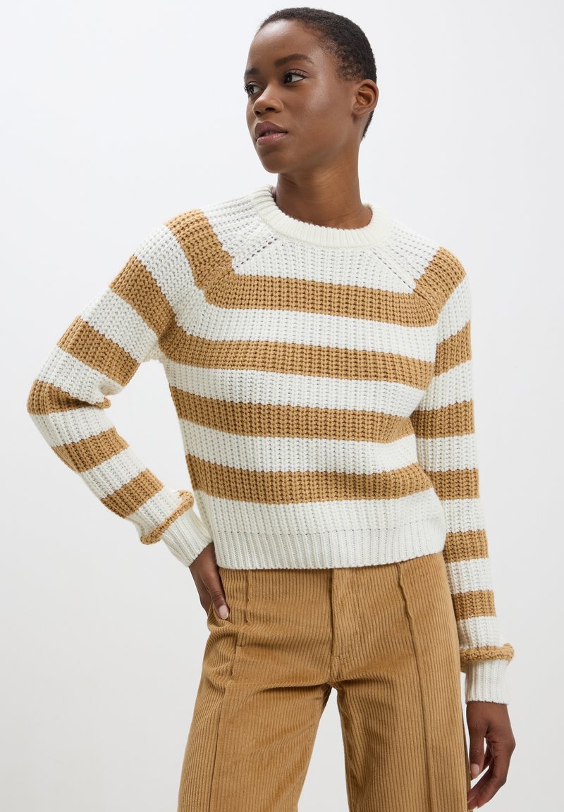 Maglione lavorato a maglia con righe verticali bianche e beige, polsini e orlo a coste, girocollo e finitura texturizzata. Abbinato a pantaloni in corduroy beige.