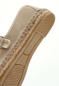 Espadrille de ante beige con una plantilla de yute trenzado y suela de goma. Cuenta con punta cerrada y costuras reforzadas a lo largo de los bordes.