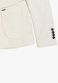 Blazer color crema con un tessuto texturizzato, dotato di una grande tasca frontale e dettagli del polsino a quattro bottoni.