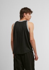 Schwarzes Tanktop mit weißen Streifen entlang des Halsausschnitts und der Armausschnitte, entspannte Passform und weicher, strukturiertes Material.