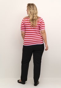 Kurzarm-Shirt mit roten und pinken Streifen, kombiniert mit schwarzen Hosen. Das Oberteil hat horizontale Streifen und eine figurnahe Passform.