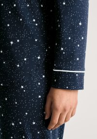 Navy pyjama set met een sterrenpatroon in het wit, van een zachte stof met contrasterende piping langs de manchetten van de mouwen.