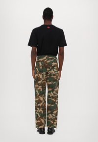 Svart bomulls T-skjorte med korte ermer og en liten rød logo på baksiden. Camo cargo-bukser med lommer, i grønne, brune og beige mønstre.