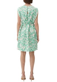 Vestito floreale verde con vita aderente, maniche a campana e dettaglio a chiave sulla schiena. Tessuto liscio con una leggera stampa floreale.