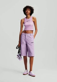 Λιλά crop top και αντίστοιχα σόρτς με τσέπες και λεπτομέρειες λογότυπου. Ολοκληρωμένο με λιλά αθλητικά παπούτσια και μια μικρή μωβ τσάντα.