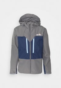 Szara i granatowa kurtka przeciwwiatrowa z kapturem, o designie w blokach kolorów, z jasnoniebieskimi akcentami na zamkach oraz logo na piersi.