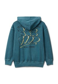 Petrolejová mikina s kapucí s grafickým textem "Pojďme vypadat jinak" a "Buď dobrý ve všech věcech" ve stylizovaném žlutém a černém písmu na zadní straně.