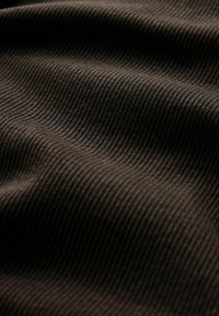 Tumepruun ribakangas, millel on tekstuuriga pind ja peened vertikaalsed jooned, mis näitavad kudumise sügavust ja dimensiooni.