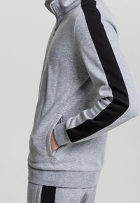 Grå zip-up sweatshirt i en bomullsmix, med svarta sidostripes, hög krage och framfickor. Mjuk textur med en figurnära design.