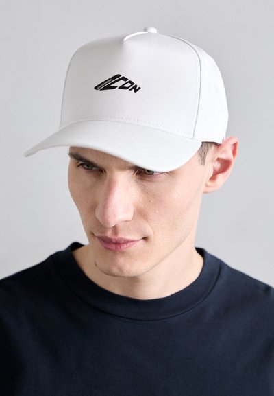 Casquette blanche avec un design structuré, arborant un logo noir à l'avant, texture de tissu lisse et visière incurvée.