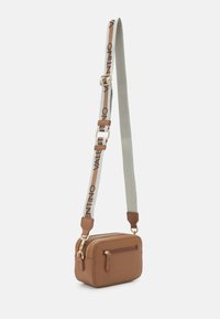 Malá obdélníková hnědá kožená crossbody taška se zlatými zipy a nastavitelným béžovým popruhem, na kterém je vytisknuto "VALENTINO" černou barvou.