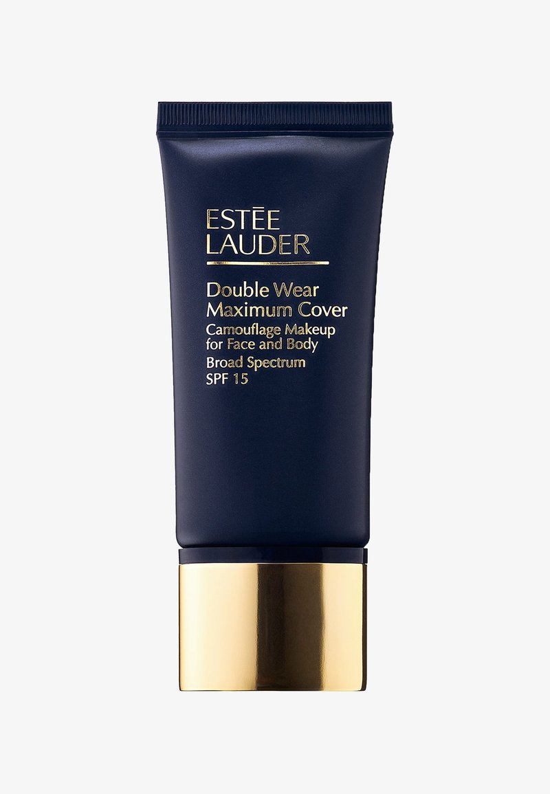 Tube écrasable bleu foncé avec des accents dorés. Le texte indique "Double Wear Maximum Cover", ce qui signifie un maquillage camouflant pour le visage et le corps. SPF 15.