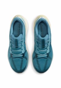 Baskets de sport bleues avec une tige en maille texturée, des lacets contrastants, un col rembourré et une semelle extérieure en caoutchouc blanc.