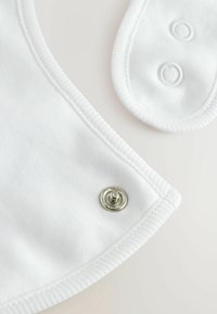 White cotton fabric with a smooth texture, featuring snapped closures and a rounded collar shape. Visible stitching around edges.