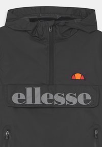 Czarna bluza z kapturem, z zamkiem z przodu, z dużym, odblaskowym logo "ellesse" na klatce piersiowej oraz małym, pomarańczowo-czerwonym półokrągłym emblematem.