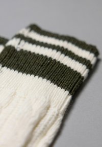 Katoenen sokken met een geribbelde textuur hebben een donkergroene boord en afwisselend witte en groene strepen op de schacht.