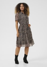 Leopardimustriga kleit lühikeste polyga, nööpide jaotusega ees, kihiline disain ja kitsendatud vöökoht. Kombineeritud mustade seemisnahast pahkluu saapadega.