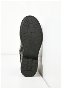 Black boot sole with textured tread pattern. Made from rubber, features a smooth finish and a slight heel. Sturdy design with logo detail.