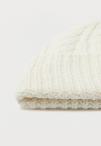 Fehér kötött gyapjú sapka, bordás hajtott szegéllyel és fonott mintával a tetején, fehér háttérrel elszigetelve.