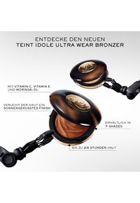 Bronzer-Kompakt mit glänzendem dunkelbraunem Deckel, goldenen Akzenten und einer glatten, gewundenen Bronzer-Oberfläche. Inklusive Applikator mit Gelenk.