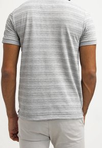 T-shirt gris à manches courtes avec des rayures horizontales, un design texturé et une coupe décontractée, avec un col et des poignets côtelés.