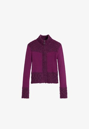 Paarse jas met ritssluiting en een geribbelde structuur, met gestructureerde gedeelten op de schouders en mouwen, en een aansluitend, kort model.