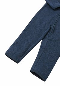 Marinblå fleece jumpsuit med långa ärmar, dragkedja fram och ribbade ärmslut. Tyget har en texturerad yta och en mjuk finish.