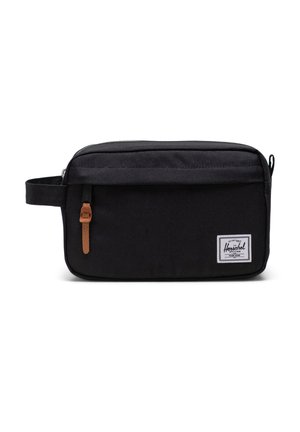 Black canvas travel bag with a rectangular shape, textured surface, leather pull tab, and a white label with navy border on the front.