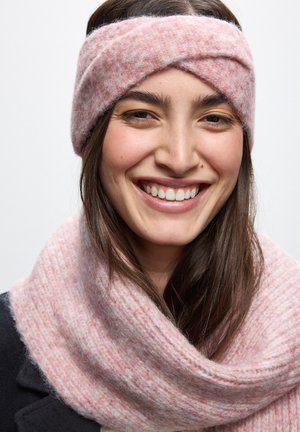 Rosa stickad pannband med en tvinnad design, i kombination med en mjuk rosa ribbad halsduk. Båda föremålen har en texturerad yta.