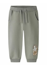 Pantalon de survêtement en coton gris avec taille côtelée, cordon de serrage, poches latérales et un motif de tigre brodé près du bas.