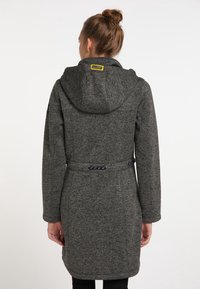 Šedý, texturovaný kabát s kapucí, nastavitelným páskem na úpravu v pase a žlutou značkou na zadní straně. Má dlouhé rukávy a mírně tapered střih.