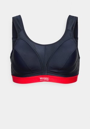 Suterã desportiva azul-marinho com copas moldadas, alças largas e uma faixa elástica vermelha na parte inferior com um logo branco. Tecido suave com design estruturado.