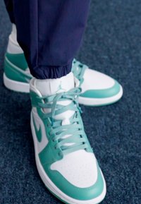 Nike Air Jordan sportbačiai balti ir mėlyni. Turėti sklandų odinį paviršių, apvalų pirštą, perforacijas ir plokščias raišteles.